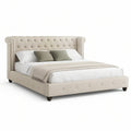 Chesterfield-Polsterbett 180 x 200 cm aus Polyester in Creme mit dunkelbraunen Holzfüssen und silberfarbenen Ziernägeln